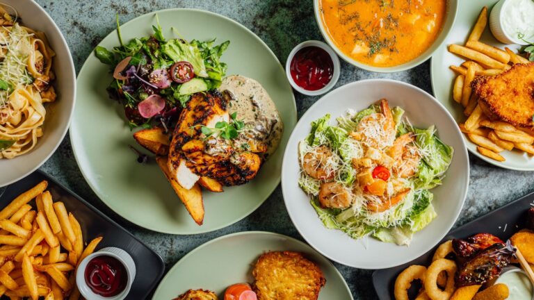 A top view of different meals with Cesar salad, french fries and cheese nuggets